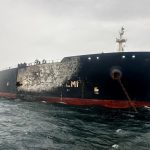 A large oil tanker at sea showing visible damage and burn marks on its hull.