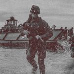 Soldiers in military gear during a coastal landing operation with a transport vessel.