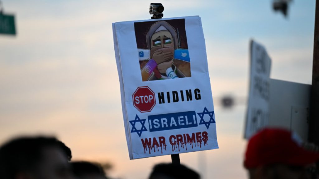 A protest sign showing a censored person and the text "Stop Hiding Israeli War Crimes" with social media icons.