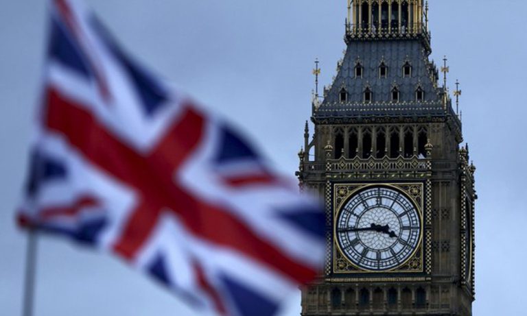 The Big Ben clock tower in London with a blurred Union Jack flag in the foreground.