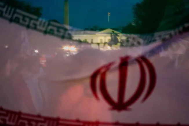 A double exposure image overlaying the Iranian flag with the White House at night.