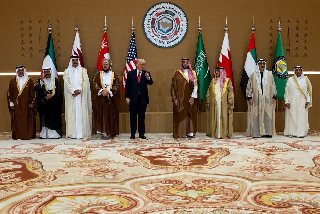 Donald Trump standing with Arab leaders at the GCC-USA Summit in front of various national flags.