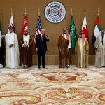 Donald Trump standing with Arab leaders at the GCC-USA Summit in front of various national flags.