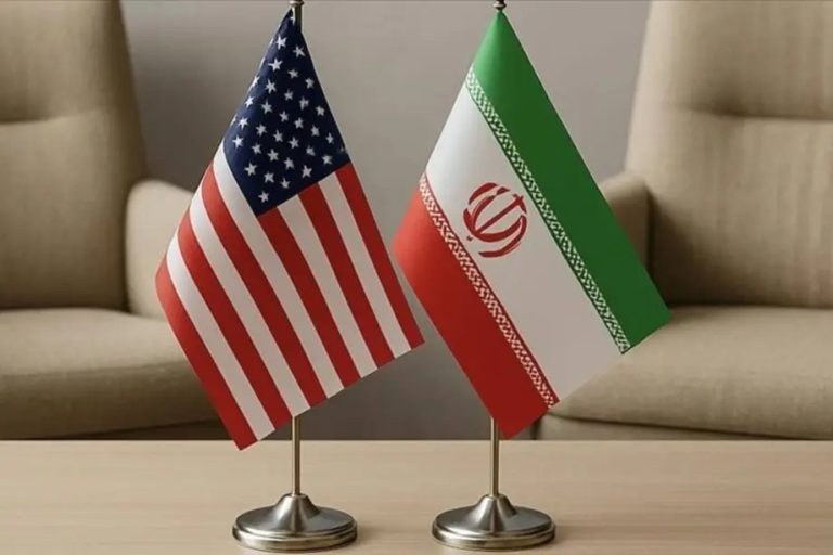 Small table flags of the United States and Iran placed side by side on a wooden table.