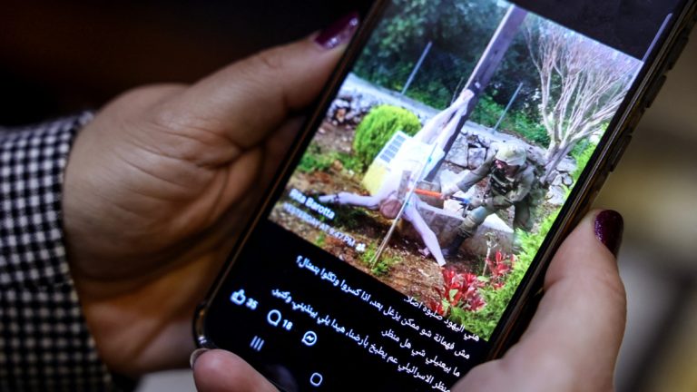 A person holding a smartphone showing a controversial image of a soldier near a religious statue.