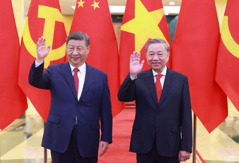 Xi Jinping and To Lam waving side-by-side in front of Chinese and Vietnamese national flags.