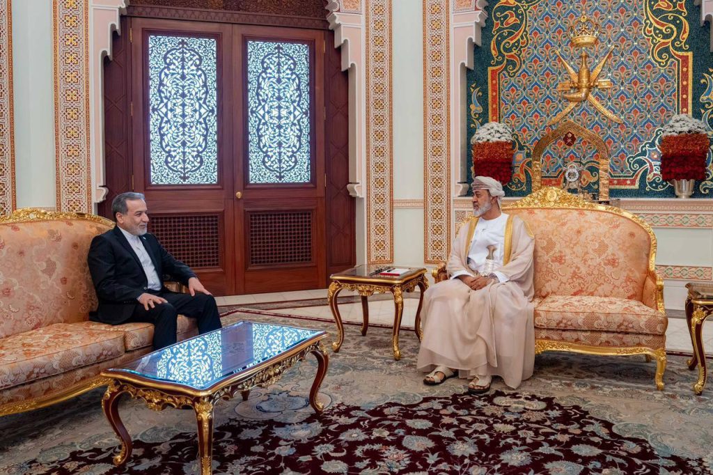 A diplomatic meeting between an Iranian official and an Omani leader in a grand palace room.
