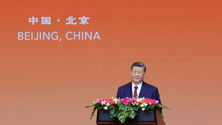 Chinese President Xi Jinping speaking at a podium during the Beijing Summit with a prominent orange background displaying Beijing China.