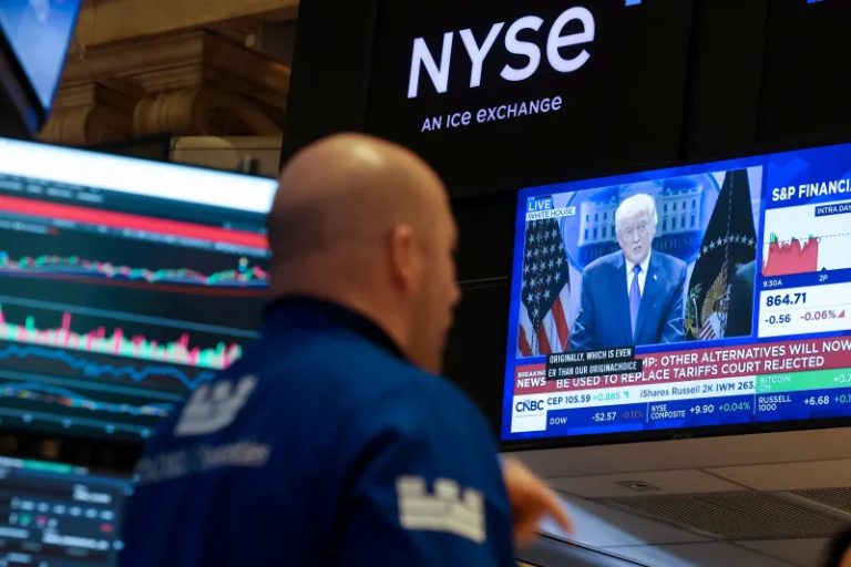 A trader at the New York Stock Exchange looking at a monitor showing a breaking news report featuring Donald Trump.