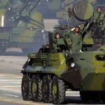 Armored vehicles and military troops in a parade.