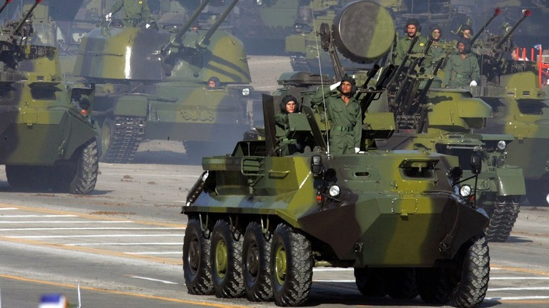 Armored vehicles and military troops in a parade.