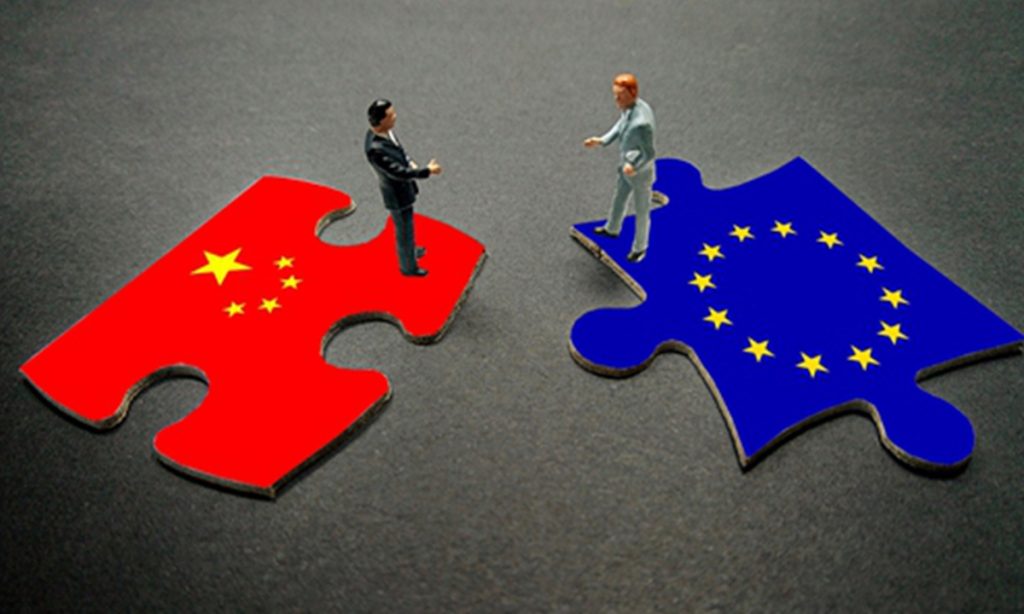 Miniature figures standing on puzzle pieces representing the flags of China and the European Union.