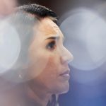 Close-up profile shot of Tulsi Gabbard with soft-focus bokeh lighting in the background.