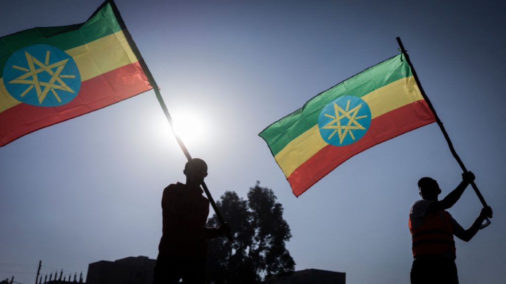 People holding Ethiopian flags against a sunset background.