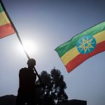 People holding Ethiopian flags against a sunset background.