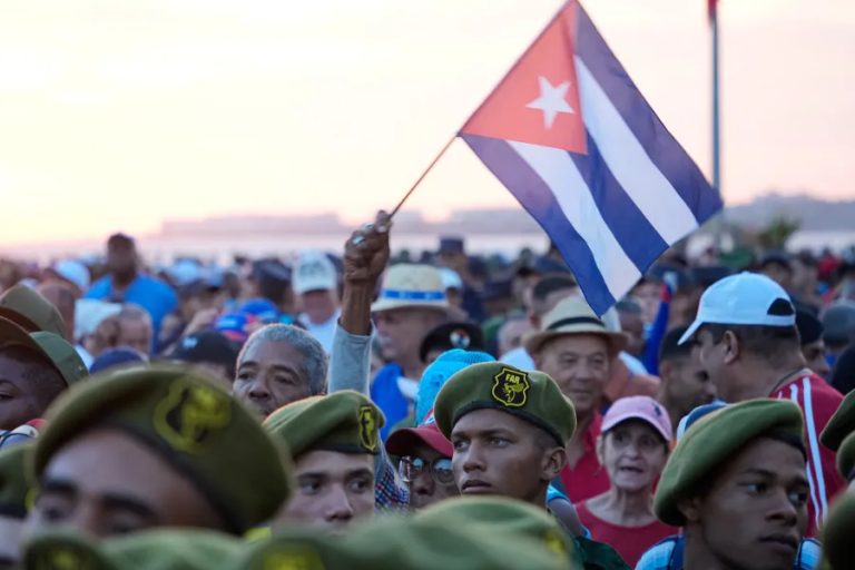 A crowd of people with a Cuban flag held high.