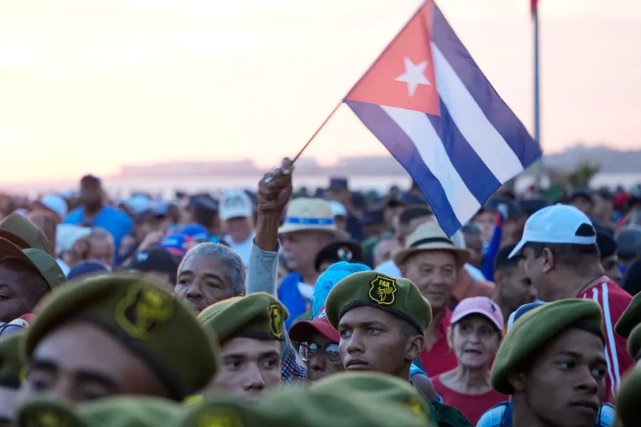 A crowd of people with a Cuban flag held high.