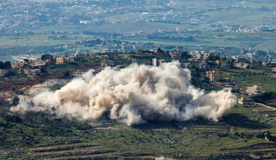 Large plume of smoke rising from an explosion in a hilly, residential area of Southern Lebanon.