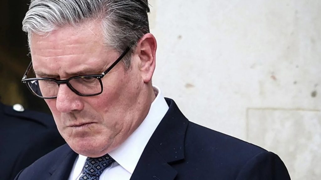 Close-up portrait of Keir Starmer looking downward with a serious expression.