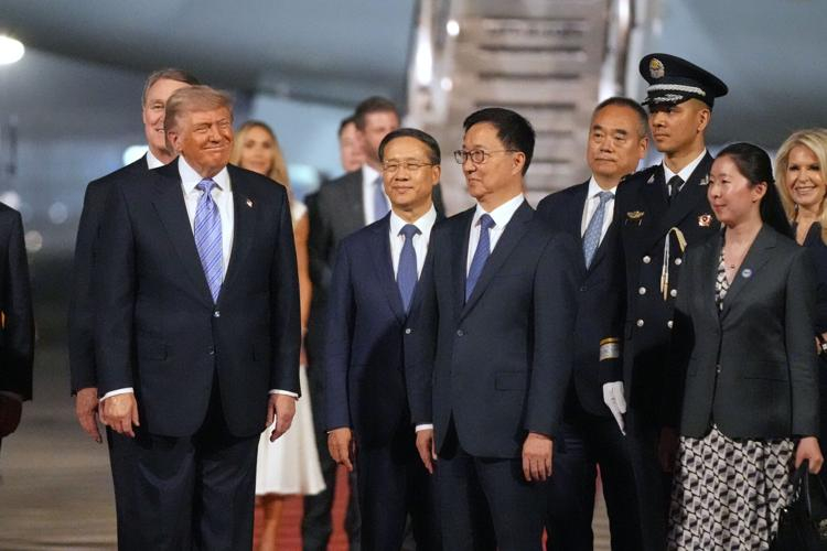 Donald Trump walking alongside international diplomats and officials on a tarmac at night, surrounded by security and government personnel.