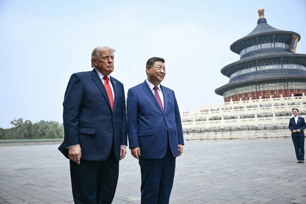 Donald Trump and Chinese President Xi Jinping standing side by side in a large stone courtyard with the Temple of Heaven in Beijing visible in the background.