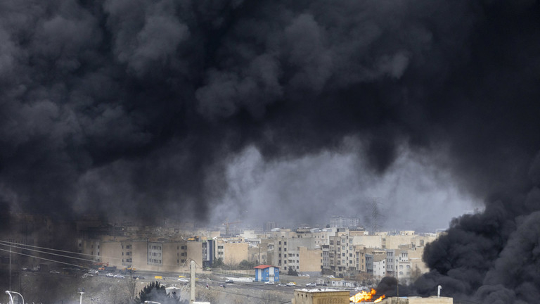 A city skyline engulfed in thick, dark smoke from an industrial fire or explosion.