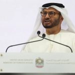 A man in traditional Emirati attire and glasses speaking behind a white podium featuring the United Arab Emirates Ministry of Foreign Affairs emblem.