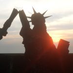 A silhouette of a crumbling Statue of Liberty against a setting sun, symbolizing national decline.