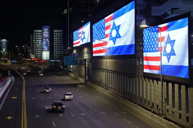 Digital billboards at night displaying the flags of the United States and Israel side-by-side.