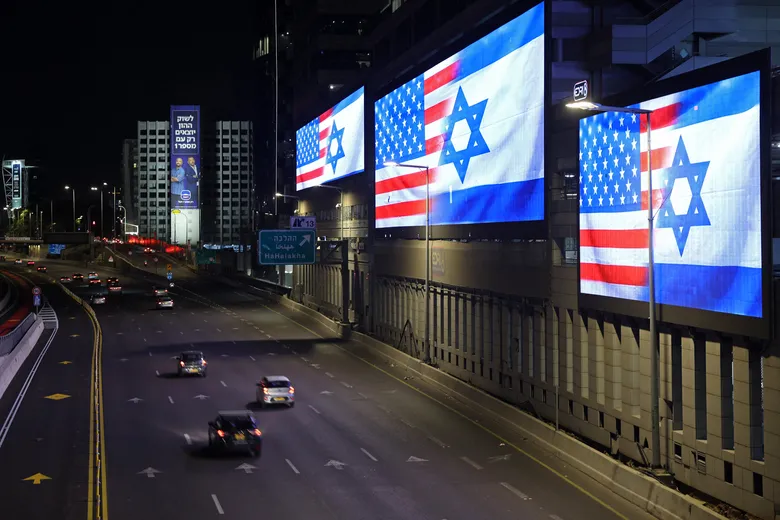 Digital billboards at night displaying the flags of the United States and Israel side-by-side.