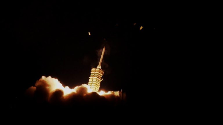 A missile launching into the night sky, representing regional defense systems.