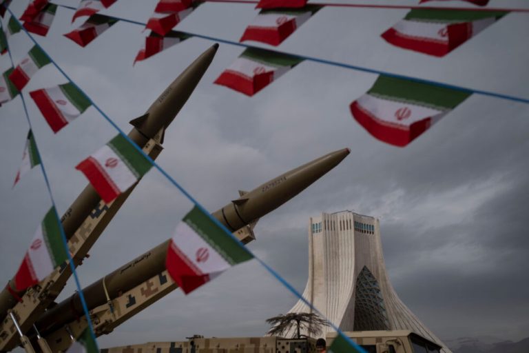 Iranian ballistic missiles displayed near the Azadi Tower with Iranian flags flying in the foreground.