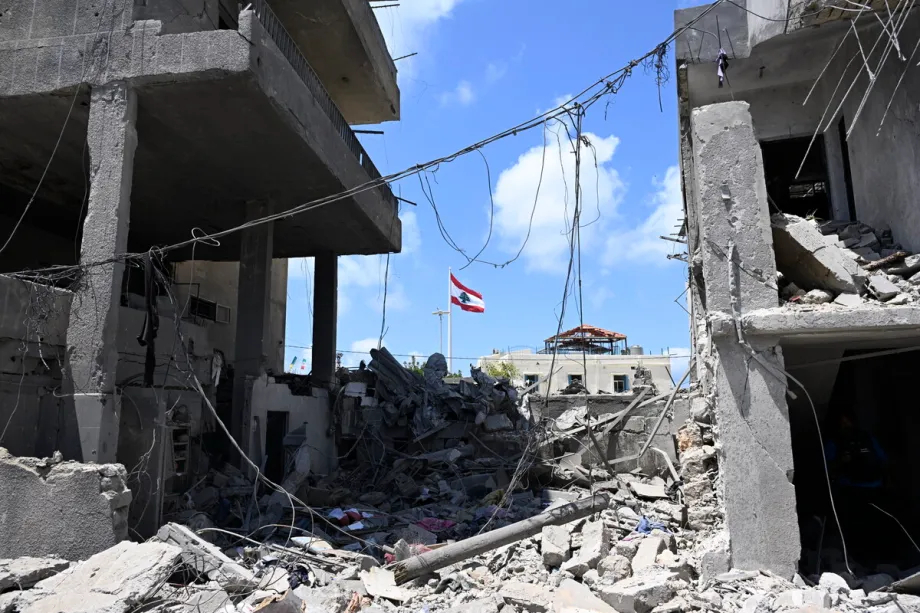 A view of a destroyed building in Lebanon with a national flag flying in the background.