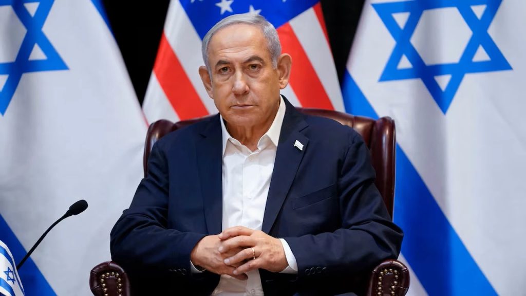 Israeli Prime Minister Benjamin Netanyahu sitting in front of Israeli and American flags.