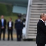 Vladimir Putin and Donald Trump shaking hands on an airfield.