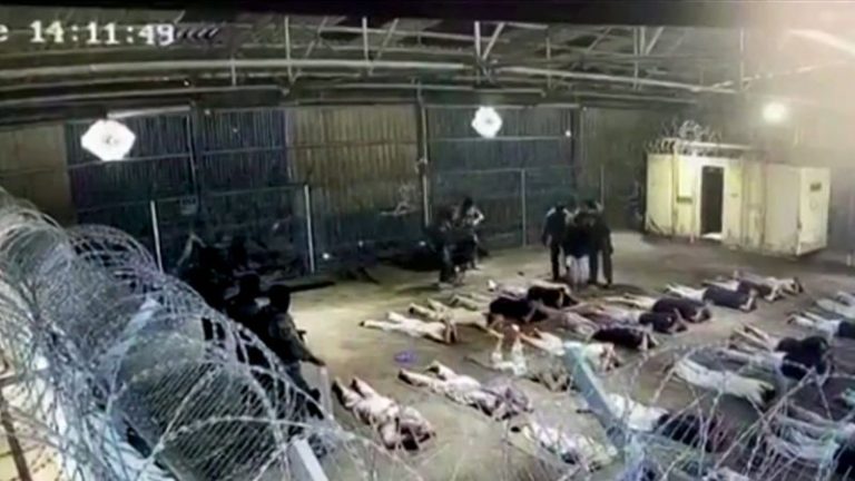 Surveillance footage showing detainees lying on the ground inside a secured facility.