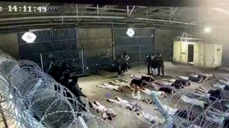 Surveillance footage showing detainees lying on the ground inside a secured facility.