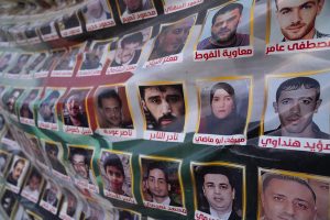 A memorial poster displayed in public featuring rows of photos of missing people in Syria.