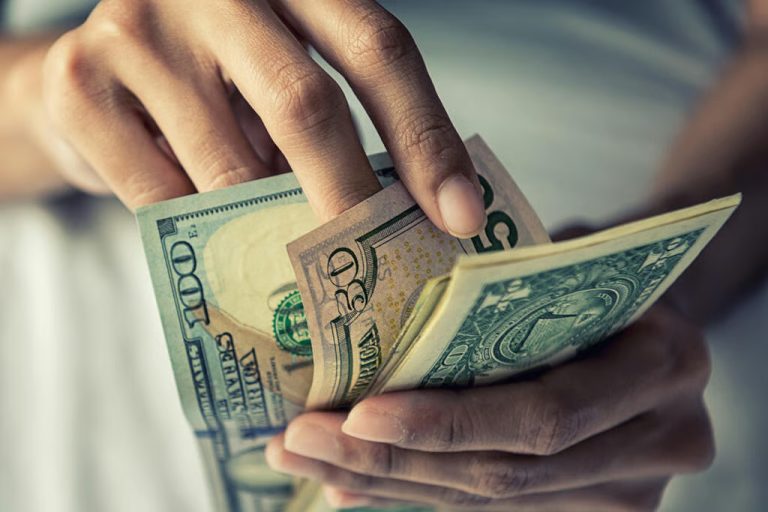 Close-up of a person's hands counting United States dollar banknotes.
