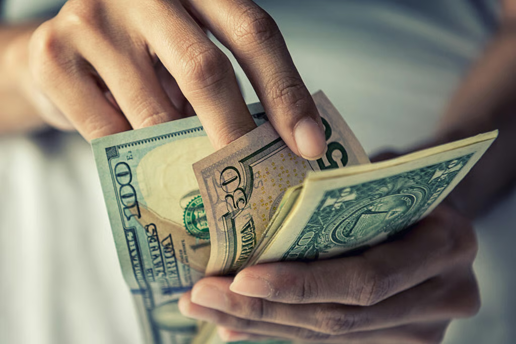Close-up of a person's hands counting United States dollar banknotes.