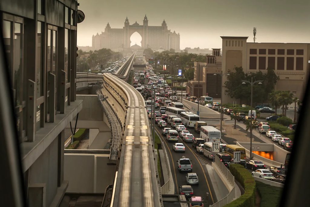Heavy traffic on a highway in the Middle East with iconic buildings in the background.
