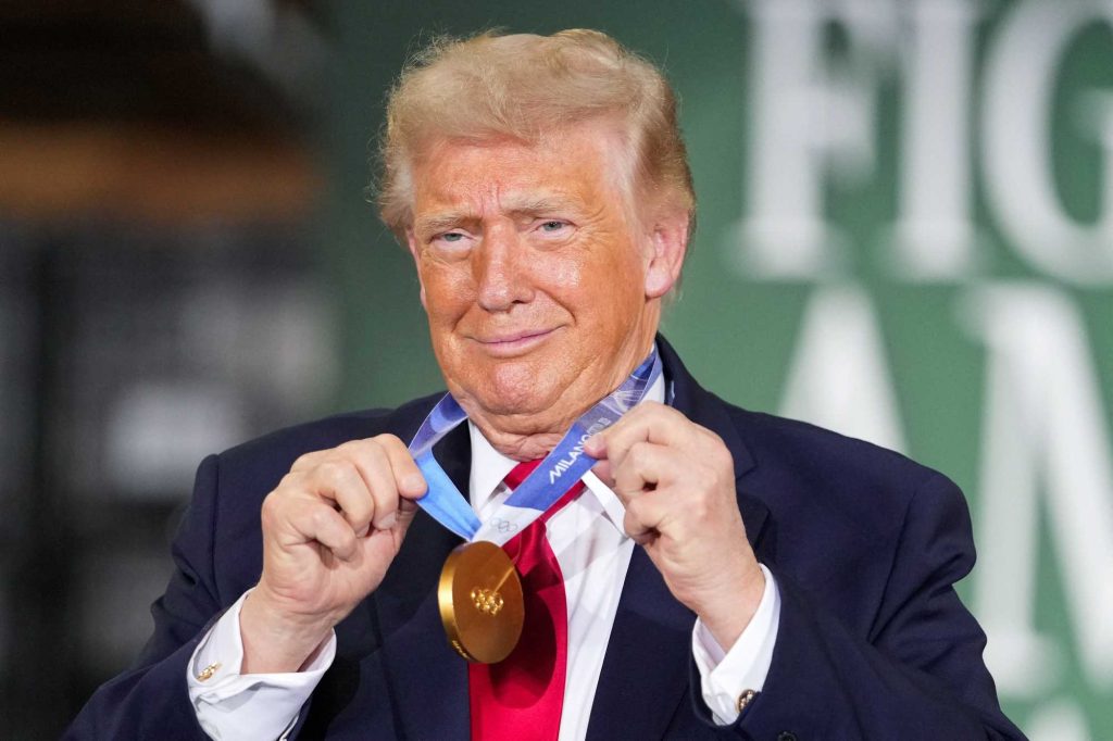 Donald Trump smiling while holding a gold medal around his neck.