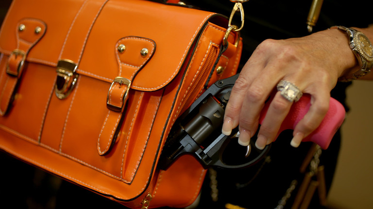 A person removing a handgun from an orange purse.