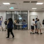 Diverse group of students talking and walking in a modern school hallway.