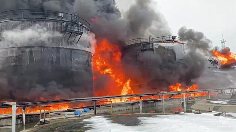 Industrial oil tanks engulfed in flames and thick black smoke after a drone attack.