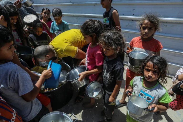 Children in Gaza holding empty pots while waiting for humanitarian aid.