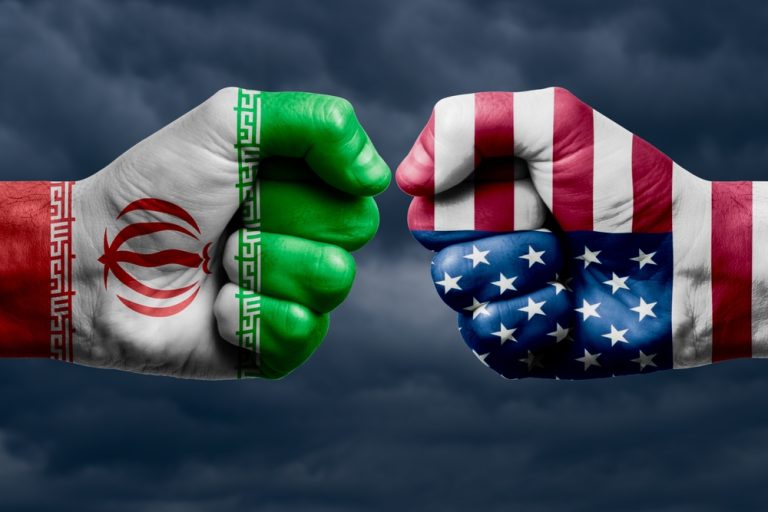 Conceptual image of two giant fists bumping, one painted with the Iranian flag and the other with the US flag, against a stormy sky.