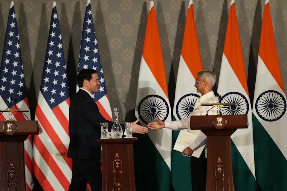 A US official and an Indian official shaking hands at a podium.