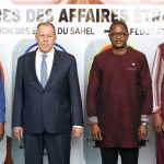 Four officials standing in a row in front of a banner during a diplomatic meeting between the Sahel and Russia.