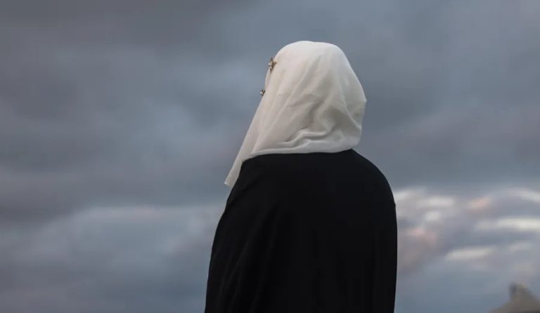 A person wearing a hijab looking out over a cloudy sky.
